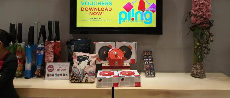 A TV above the cashier counter showing a voucher app promotion